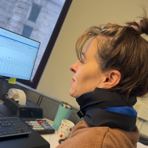 Person sitting at a desk with a computer monitor and keyboard in an office setting